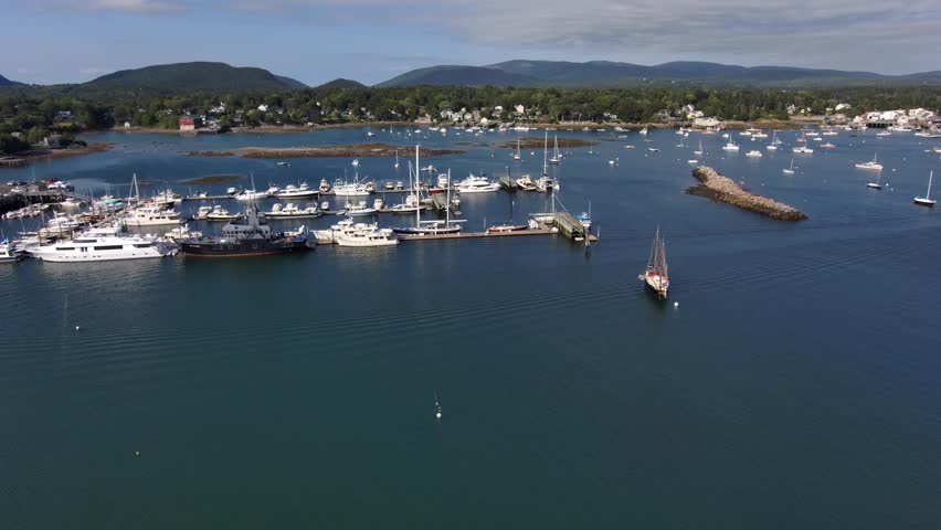 Southwest Harbor - Mount Desert Island, Maine. Moving aerial view from above. Small boats and sailboats anchored in the marina.