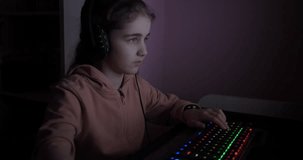 Teenager Girl Plays Computer Video Game in Dark Room, Cybersport Gaming, Children Gaming Addiction.Child Gamer in Headphones Plays Loses Round in Online Shooter on Modern PC. Video Game Live Streaming
