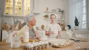 Smiling happy child girl helps cook to granny in kitchen. Her face dirty in flour, granny touches her nose. Cooking together, family sweet moments. Portrait of pre-teen laughing girl in cook's cap - Powered by Shutterstock - Get 15% off with code: PIKWIZARD15