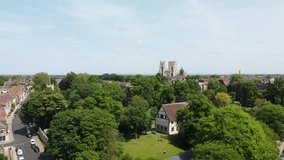 YORK, UK - MAY 29, 2023: An aerial shot flying towards York Minster over the musuem gardens and yorkshire museum with people enjoying a sunny day