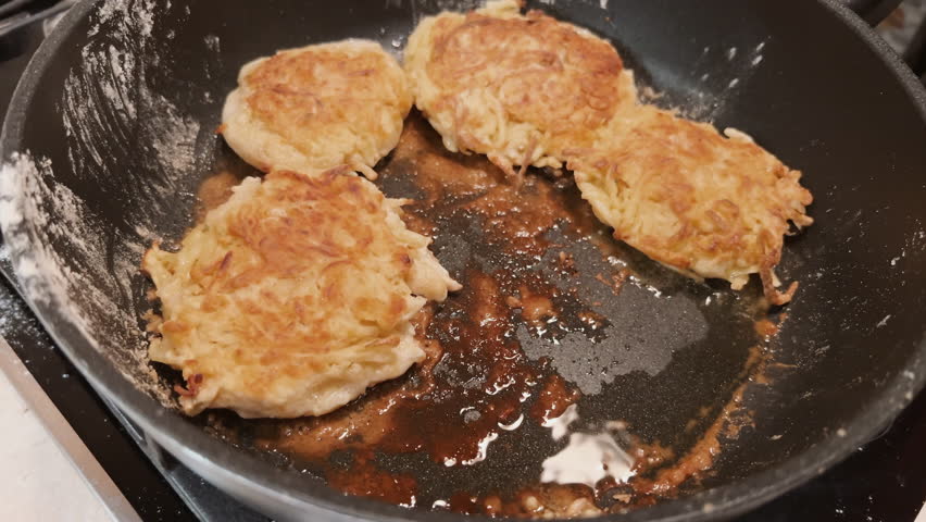 POV cooking potato pancakes on frying pan. Frying flapjacks at home. Tasty rustic food. Preparing crispy battercakes from flour and potato. Film grain pixel texture. Soft focus. Blur. Live camera Royalty-Free Stock Footage #3405944419