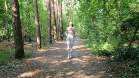 Join a young and determined fitness enthusiast as she embarks on a refreshing run through the lush green forest. This slow motion video showcases her commitment to a healthy lifestyle, running along a