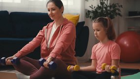 Mother and child weight training at home with an online tutorial on laptop