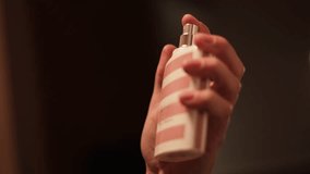 Close up of unknown woman's hand elegantly holding and spraying perfume in pink and white stripped bottle. Female applying new luxury fragrance from cosmetic store as final step of beauty routine. - Powered by Shutterstock - Get 15% off with code: PIKWIZARD15