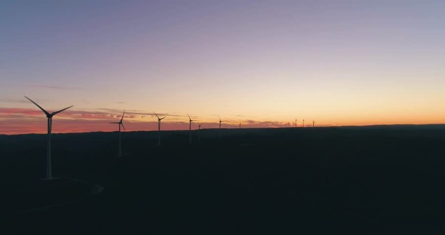 Aerial wind farm turbine generators at dusk. Clean renewable energy power production concept. Algarve countryside. Portugal. Royalty-Free Stock Footage #34060477