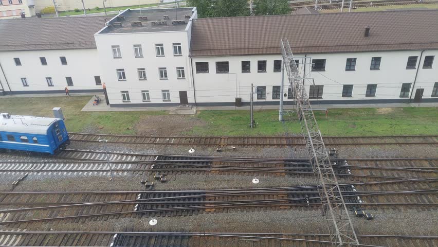 At the station the railroad tracks are graveled and electrified. A shunting diesel locomotive with a passenger car runs along the switches. There is an administrative building with a metal roof