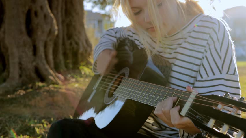 Teenage girls playing the guitar in the park. Girl play solo guitar in green nature park. 