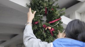A woman hangs a Christmas wreath from a spruce branch on the porch above the door of the house. - Powered by Shutterstock - Get 15% off with code: PIKWIZARD15