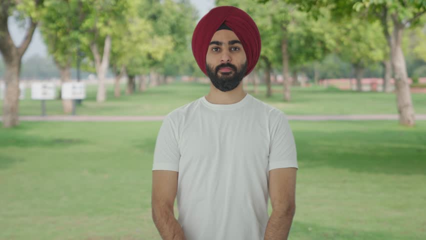 Confident Sikh Indian man standing crossed hands in park