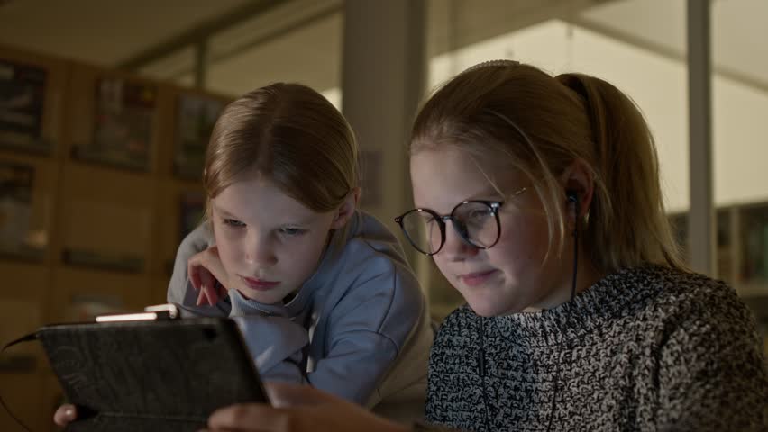 Two girls siblings surfing web pages in a room on a tablet computer Royalty-Free Stock Footage #3406373607