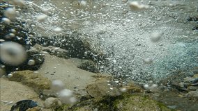 Camera moves forwards towards flow of mountain river mixed with air bubbles flow into sea over sand seabed covered with shells and stones, Slow motion, Close up - Powered by Shutterstock - Get 15% off with code: PIKWIZARD15