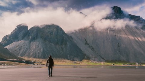 Aerial Flyover Over Lonely Man Figure Walking Vast Nordic Mountain Landscape Beautiful Clouds Arctic Environment Majesty Of Nature Facing Fears Concept