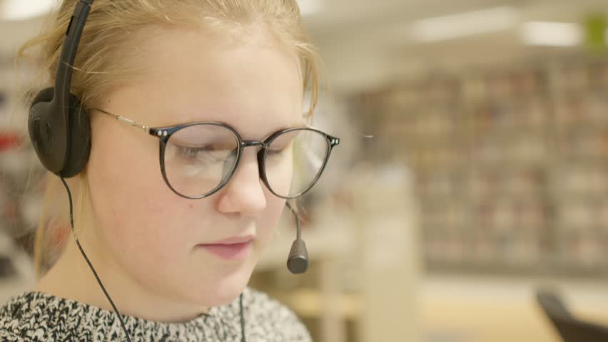 The young girl at work, wearing glasses, with headphones and microphone Royalty-Free Stock Footage #3406532355