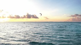 Sunset sky over the Indian Ocean bay with kiteboarders riding kiteboards with green bright power kite. Active sport people and beauty in Nature concept image. Le Morne beach, Mauritius 4K video.