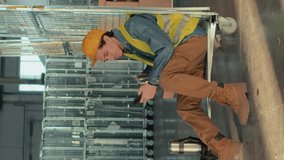 Full side vertical shot of Biracial male warehouse worker drinking tea or coffee and using smartphone sitting on stock cart and smiling during break at workplace - Powered by Shutterstock - Get 15% off with code: PIKWIZARD15