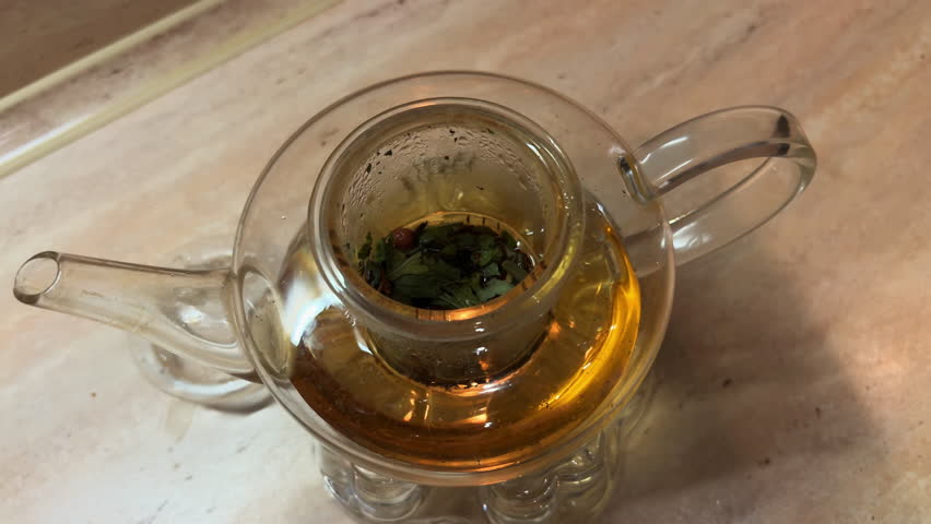 POV pouring boiling water into tea pot. Herbal tea with berries in a glass pot. Cozy time at home. Enjoy hot drink. Film grain pixel texture. Soft focus. Blur. Live camera