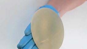 A plastic surgeon demonstrates breast implants. Vertical video.