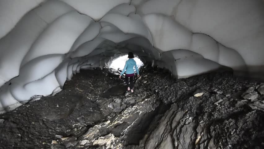 Lauterbrunnen, Switzerland - 09-11-2016 - Active female tourist hiking inside a snow cave near the Jungfrau mountain