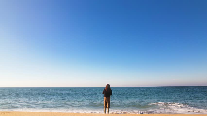 Woman fishing near the surf on peaceful and beautiful beach - with golden sand and turquoise water