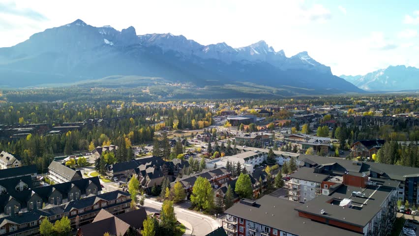 Aerial view of Town of Canmore in a autumn sunny day. Canadian Rockies mountain range in the background. Alberta, Canada. Royalty-Free Stock Footage #3406919437