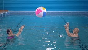 training for adults. woman and man in the pool. throwing the ball to each other. throwing a beach ball. Slow motion video. High-quality shooting in 4K format.
