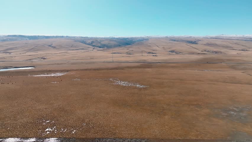 Aerial drone view of the plains near Qinghai Lake.  A 2 way road surrounds the lake.
