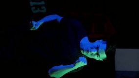 Boxer in unusual color: green and blue lighting shines on the boxer. Punches in the direction of the camera. Slow-motion and vertical video.
