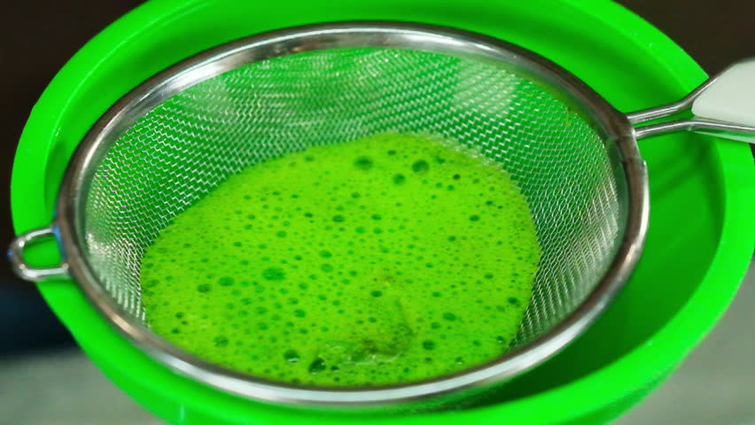 Man stirs egg mixture in sieve with spoon. Professional chef demonstrates proper way to prepare base for dish using funnel
