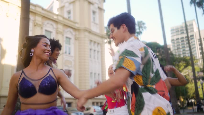 Vibrant Street Dance at Brazilian Carnival, Joyous Group Embracing Festive Spirits. Couple and Friends Celebrating in Colorful Costumes Amidst Urban Backdrop. Royalty-Free Stock Footage #3407361045