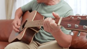 Close-up view of the hand of an elderly Asian man. Playing guitar and singing at home He is happy with his retired life. music concept, live performance