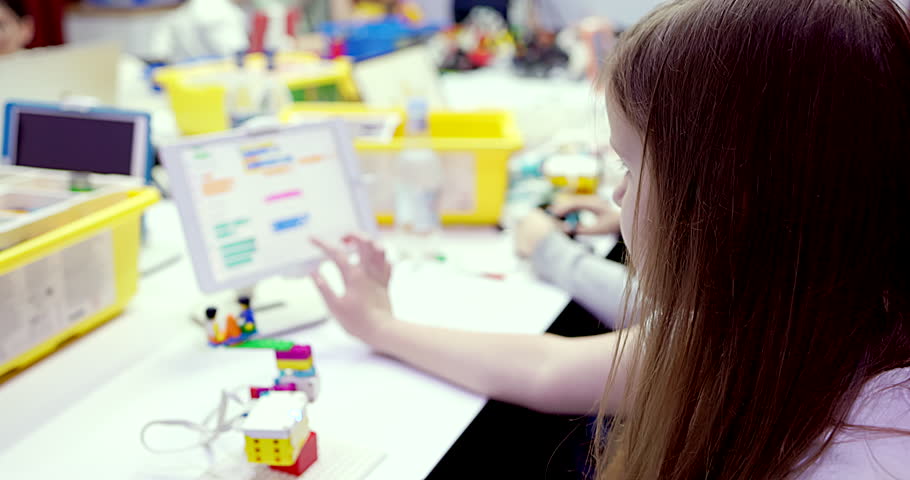 Children at school learning programming robot toy using tablet game in classroom