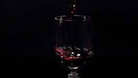 Red Wine is poured into glass in Slow Motion on a black background