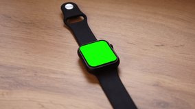 Smartwatch with a green screen on a wooden table
