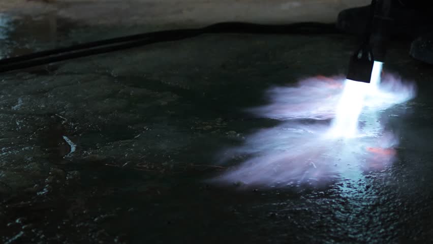 A fiery stream from a kerosene torch to snow and ice