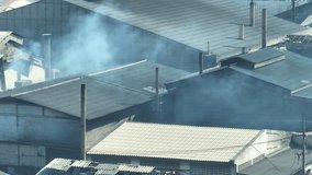 Industrial estates release plumes of smoke, staining the sky with pollution, as seen from above through an aerial view drone. Greenhouse gases and Carbon monoxide concept.
