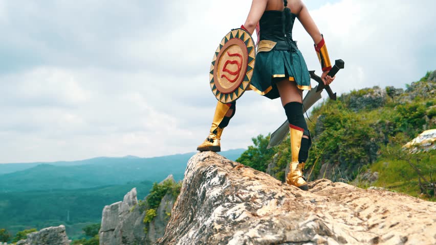 a female warrior holding a sword and golden shield standing on a cliff very bravely in the daytime