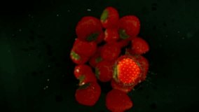 Super slow motion of falling strawberries into water on black background. Filmed on high speed cinema camera, 1000 fps. Speed ramp effect.