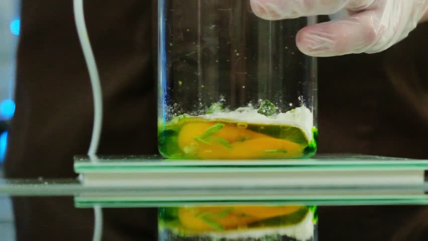 Transparent measuring cup containing mixture of raw egg and greenery stands on scale. Fresh ingredients ready for blending