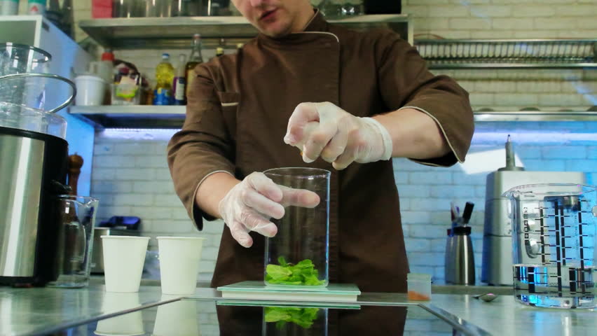 Proficient chef expertly breaks chicken egg into transparent measuring cup containing spinach. Initiation of crafting new gastronomic masterpiece