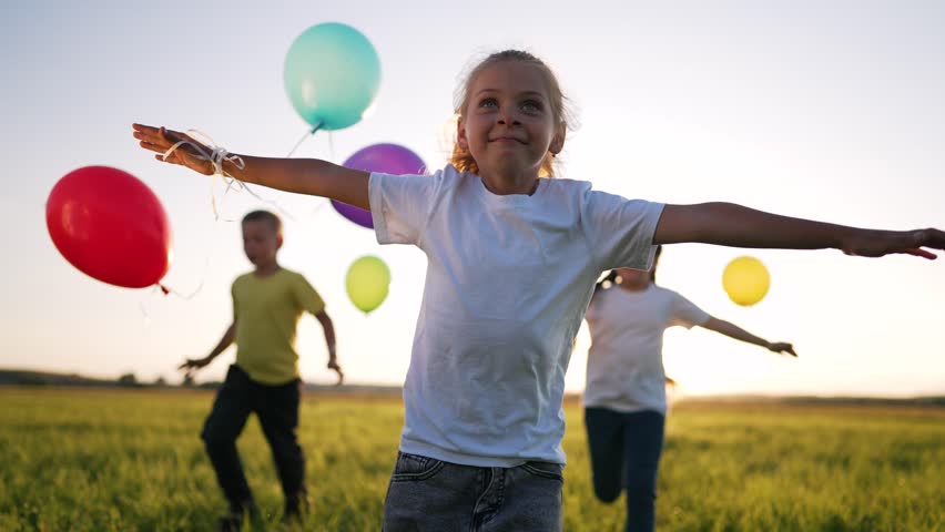 Happy family concept.Child run together and play in nature in summer with balloons.Balloons at sunset, celebration of summer freedom in hand of child.Kids run and play with colorful balloons in park