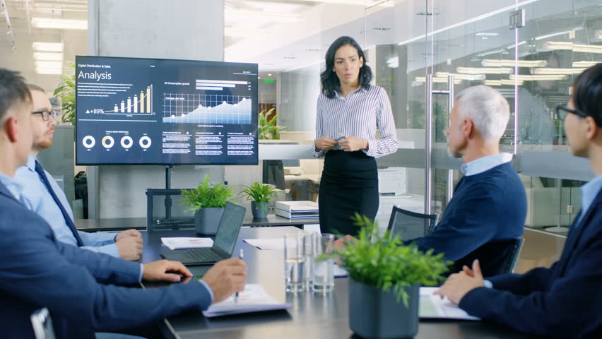 Beautiful Businesswoman Gives Report Presentation to Her Business Colleagues in the Conference Room, She Shows Graphics, Pie Charts and Company's Growth on the Wall TV.  Royalty-Free Stock Footage #34080082
