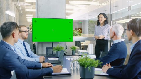 Beautiful Businesswoman Gives Report Presentation to Her Business Colleagues in the Conference Room, She Interacts with Wall TV with Green Chroma Key Screen. Shot on RED EPIC-W 8K Helium  Camera.