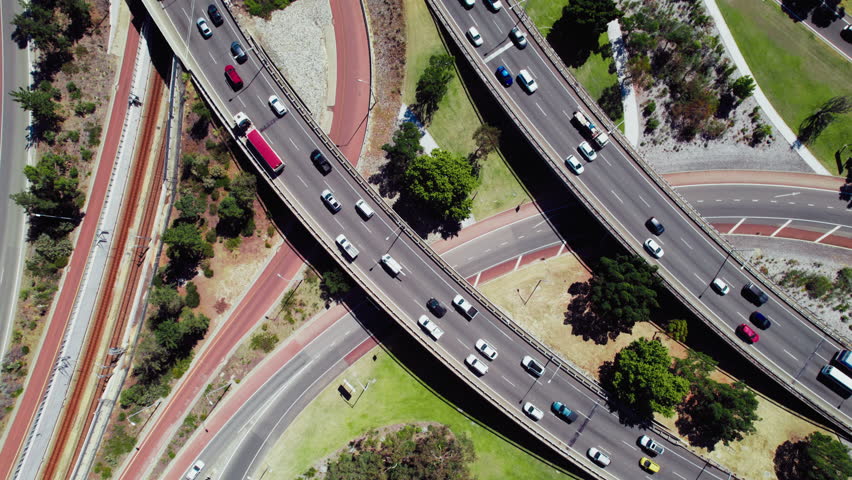 Top down view at a busy traffic junction in Perth, Australia. Aerial view of cars and metro trains smoothly move around, depicting how the city is designed and how people get around