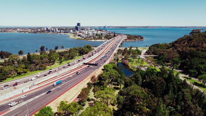 Aerial view capturing the bustling highway next to the Swan River in Perth City on a sunny day in Western Australia, landscape with the river, parks and bay with the bridge