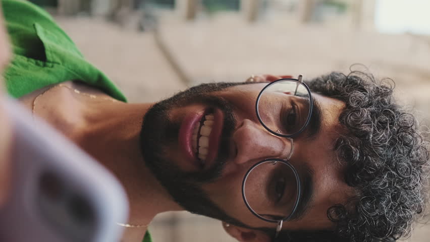 Vertical video, Close-up, homosexual couple looking at mobile phone together on street of old city
