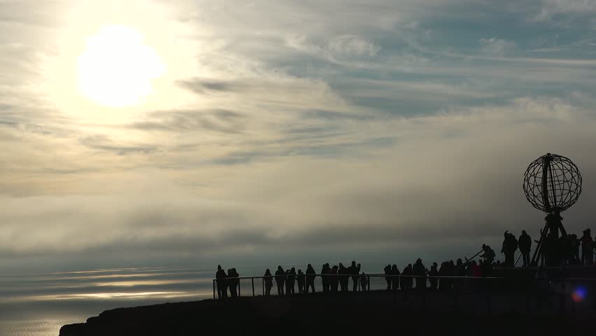 Nordkapp at Sunset with Colorful Clouds and Silhouette of Globe Monument and people. Globe monument at North Cape at midnight, island of Mageroya, Norway