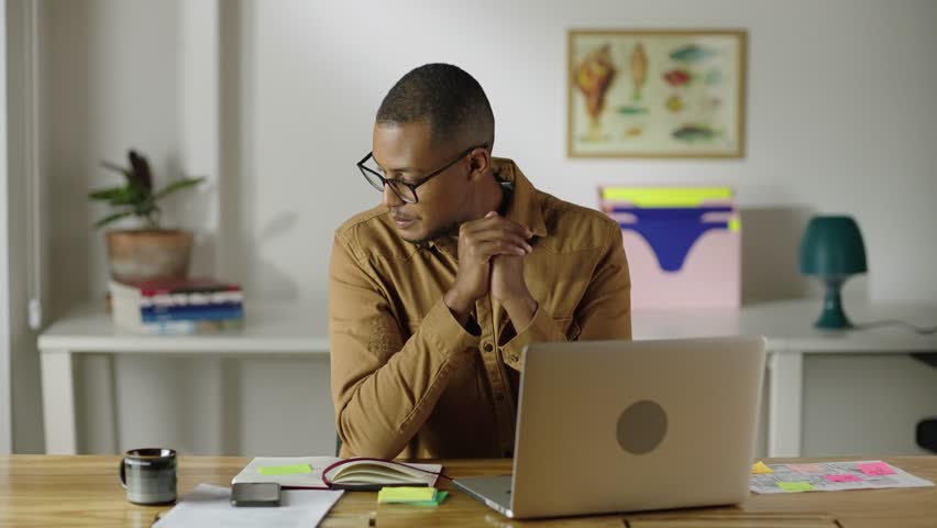 Thoughtful serious young african american man student writer sit at home office desk with laptop thinking of inspiration search problem solution ideas lost in thoughts concept dreaming looking away
 Royalty-Free Stock Footage #3408075115