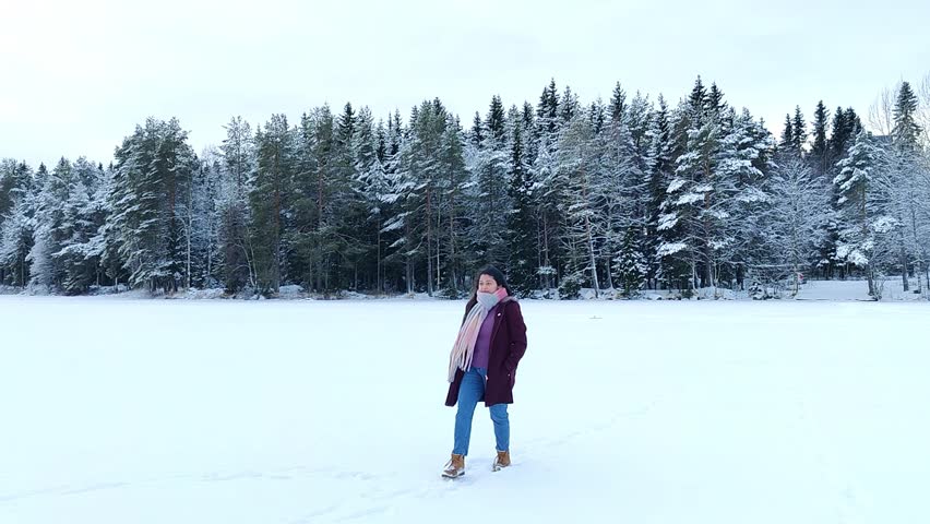 A woman enjoying and taking pictures of snow landscape. Cheerful girl enjoying beautiful winter day. Carefree lady having joyful emotions outdoor. Winter concept. Slow motion