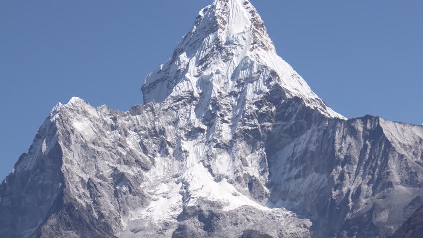 Snow covered peak Ama Dablam rise above landscape of Himalayan mountains. Trekking in Nepal to see highest mountains in world. Heat haze effect at hot. Summit with rocky massif and glaciers on slope Royalty-Free Stock Footage #3408203697