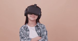 A girl having fun with game while wearing virtual reality glasses. Isolated on brown background in studio.